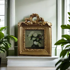 Antique gold picture frame with ornate bow relief featuring a vintage floral painting