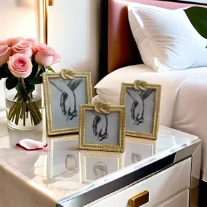 Detailed view of luxury gold rope knot picture frames on bedside table with roses.