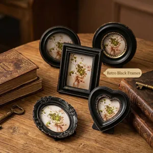Vintage distressed black and gold picture frames with botanical prints on wooden desk