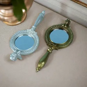 Detail von europäischen Vintage-Handspiegeln mit verzierten Harzschnitzereien in Gold und Silber