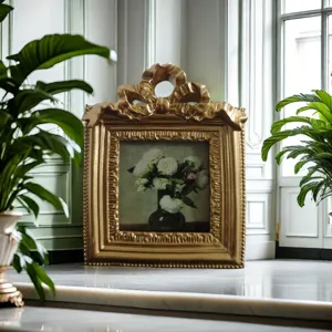 Close-up of an ornate golden picture frame featuring a bow design and elegant rose painting.