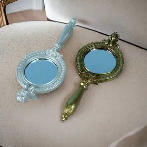 Detailaufnahme europäischer Vintage-Handspiegel mit verzierten, geschnitzten Harzgriffen