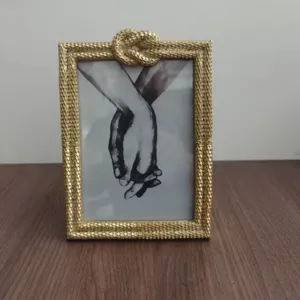Luxury gold metal photo frame with braided texture and decorative rope knot for home decor.