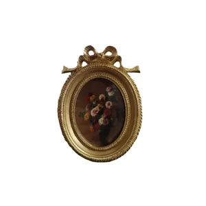 Vintage gold oval picture frame with elegant bow top and classic floral oil painting
