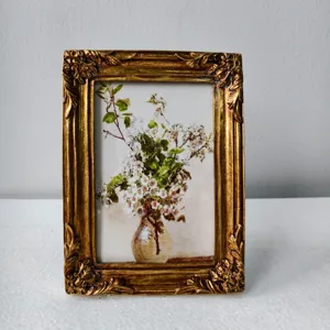 Cornice portafoto vintage in resina dorata con stampa floreale, elegante telaio rettangolare.