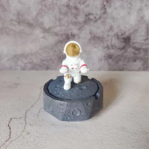 Detailed shot of resin astronaut figurine on moon surface base for modern desktop decor.