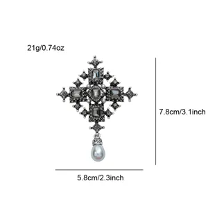 Close-up of vintage gothic cross brooch with grey crystals and a pearl teardrop dangle