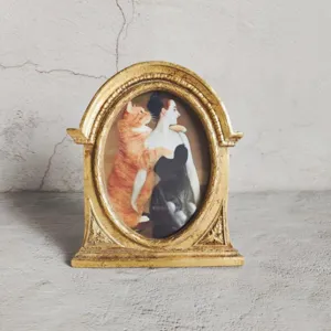 Detailed view of an ornate vintage golden resin photo frame featuring a cat portrait painting