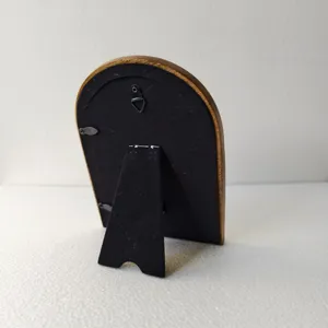 Detail view of the arched photo frame back with black velvet backing and metal stand.