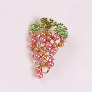 Detail view of an elegant grape brooch with pink pearls and green crystals.