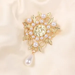 Primer plano de un broche dorado de estilo barroco vintage con elegantes perlas blancas