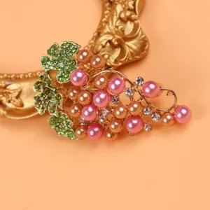Macro view of an elegant grape brooch featuring pink pearls and green rhinestones