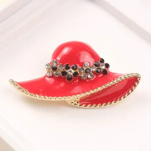 Detail view of a stylish red enamel hat brooch with sparkling rhinestones and gold trim