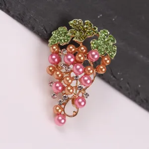 Detailed macro view of an elegant grape brooch with pink pearls and green crystal leaves.