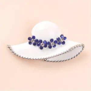 Detailed close-up of a white enamel hat brooch with sparkling blue rhinestones.