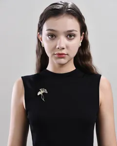 Elegante gouden ginkgoblad broche accessoire op een zwarte jurk gedragen door een model.