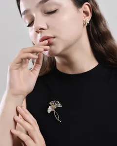 Detailopname van een vintage gouden ginkgobladbroche met kristallen gedragen door model