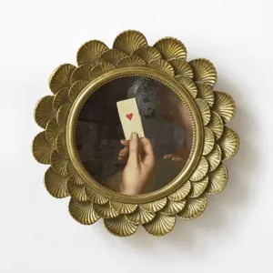 Detail of ornate gold scalloped round picture frame with vintage heart card print
