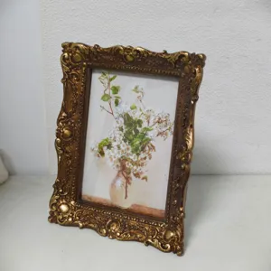 Ornate vintage gold embossed photo frame featuring a white floral still life painting.