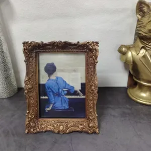 Detailed view of an ornate vintage gold picture frame with classic art print on desk