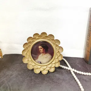Vintage ornate gold round photo frame with classical portrait on elegant stone surface