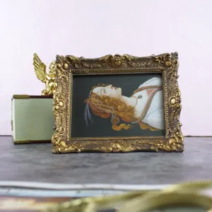 Vintage gold ornate rectangular picture frame with classical portrait on pink background