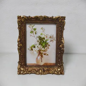 Ornate vintage gold picture frame featuring classic floral artwork for elegant desktop decor.