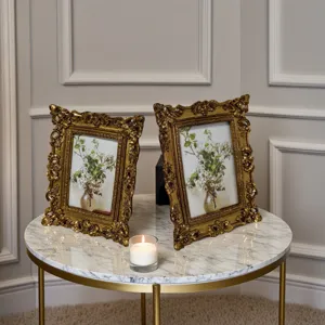 Eleganti cornici per foto dorate decorate vintage con arte floreale su tavolo di marmo