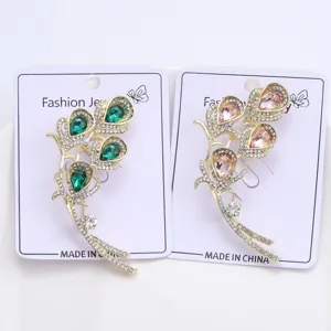 Detail view of crystal calla lily brooches in emerald green and pink shades.
