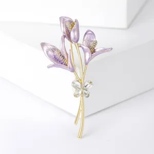 Detalle de cerca del broche de ramo de flores de esmalte morado con mariposa de cristal.