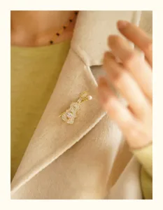 Close-up of elegant gold-toned violin brooch with pearl and cubic zirconia details