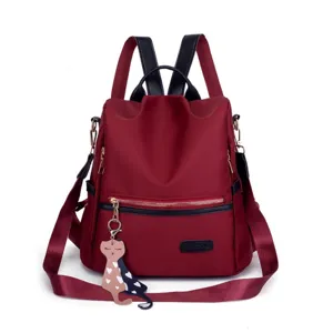 Close-up detail of burgundy Oxford cloth anti-theft backpack with cute cat charm attachment