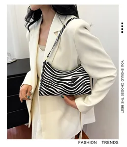 Stylish zebra print underarm bag held by a fashion model wearing a chic white blazer.