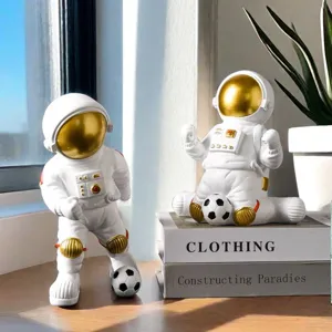 White and gold astronaut figurines playing soccer displayed on decorative books