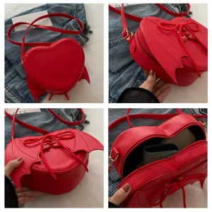 Detailweergave van hartvormige duivelsvleugel crossbodytas met vleugels en binnenruimte.