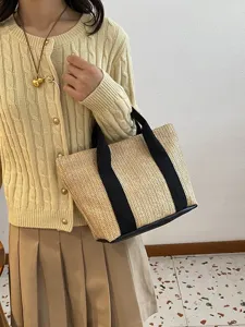 Vista detallada de un bolso de paja tejido sostenido por una modelo con estilo