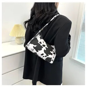 Back view detail showing a trendy cow-print baguette bag paired with a black blazer jacket