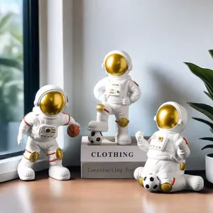 Decorative set of three white and gold astronaut figurines in basketball and soccer sports poses