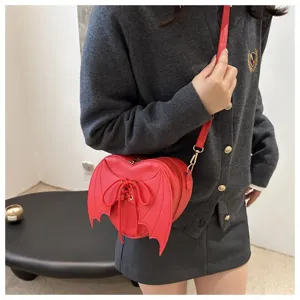 Levendige rode hartvormige crossbodytas met gotische duivelsvleugels op een model