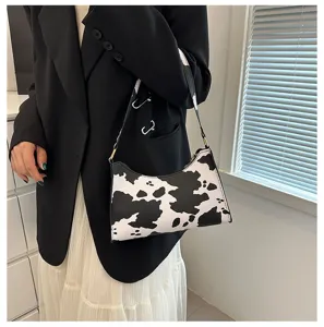Stylish black and white cow print baguette bag shown in a lifestyle fashion shot
