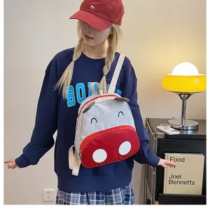 Süßer grau-roter Kuh-Cartoon-Rucksack für Kinder, getragen von einem Modell im Haus
