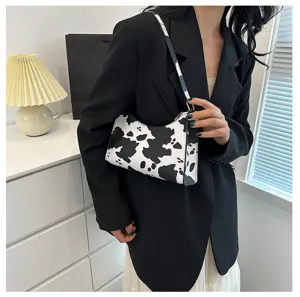 Stylish women's vintage cow print underarm bag paired with a modern black blazer outfit