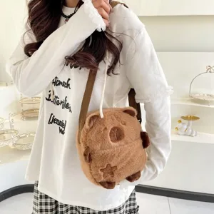 Détail d'un mignon sac à bandoulière en peluche de capybara marron porté par un mannequin