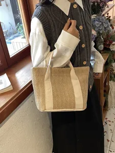 Primer plano de un bolso de paja tejido con correas de lona blancas bajo el sol