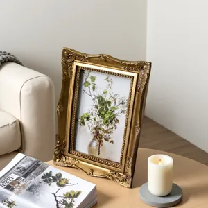 Ornate vintage gold relief photo frame with floral art on a stylish wooden table