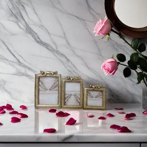 Detail of three luxury golden resin picture frames with animal motifs on marble surface