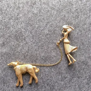 Broche vintage en métal doré représentant une femme élégante promenant un chien