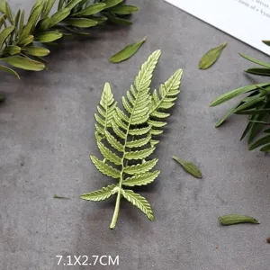 Gedetailleerde weergave van een vintage groene varenbladbroche met metalen textuur.