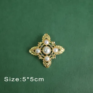 Close-up of a vintage Baroque style brooch with pearls and crystals on green background.
