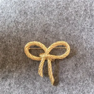 Détail d'une broche nœud doré vintage avec design tissé texturé pour mode féminine